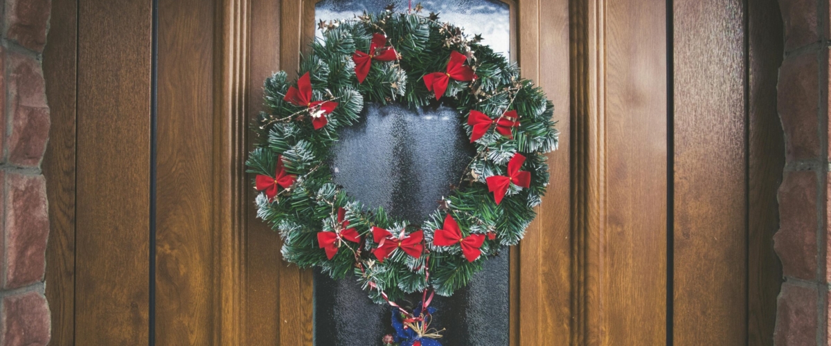 A beautifully decorated wooden door with a festive wreath and holiday ornaments.